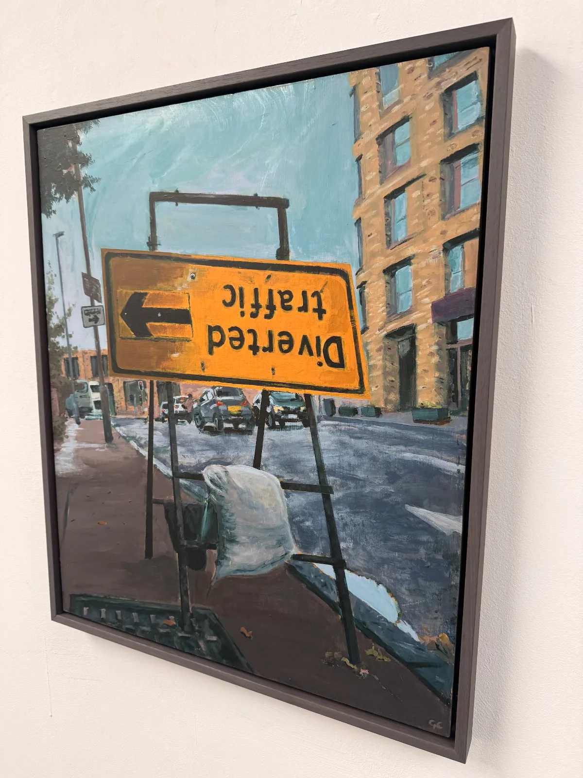 A picture of a framed painting of an upside-down Diverted Traffic roadsign